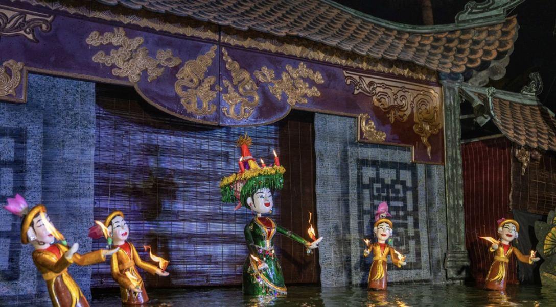 Cảnh diễn ban đêm với các con rối cầm đèn nến trên mặt nước